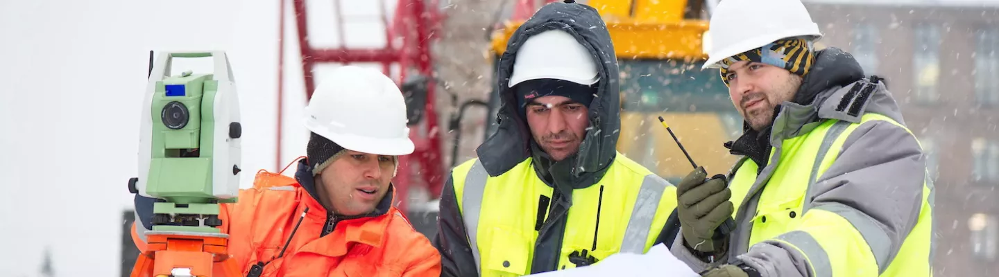 workers in safety vests and hard hats at a construction site in the winter