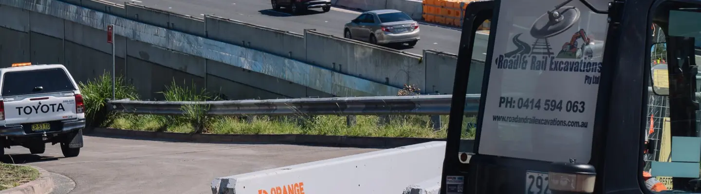 Various types of roadside safety barriers installed along a highway to protect drivers and pedestrians.