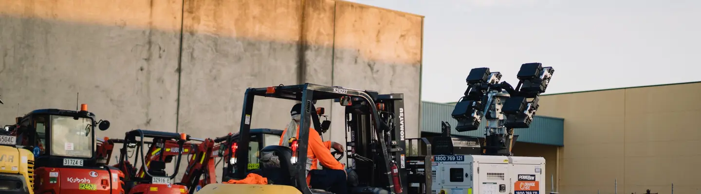 A man driving a truck equipped with a mounted plate compactor on top, used for compacting soil at a construction site.