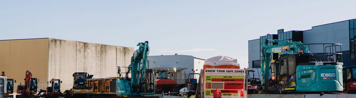 A variety of construction machines parked on the ground, illustrating diverse equipment used at a building site.
