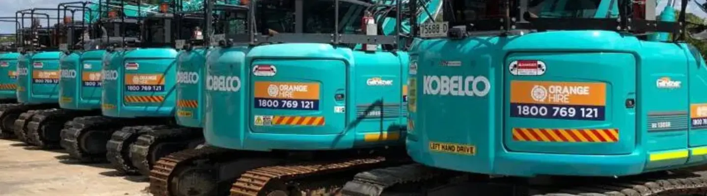 Row of excavators at a construction site, highlighting equipment readiness and safety for barrier installation.