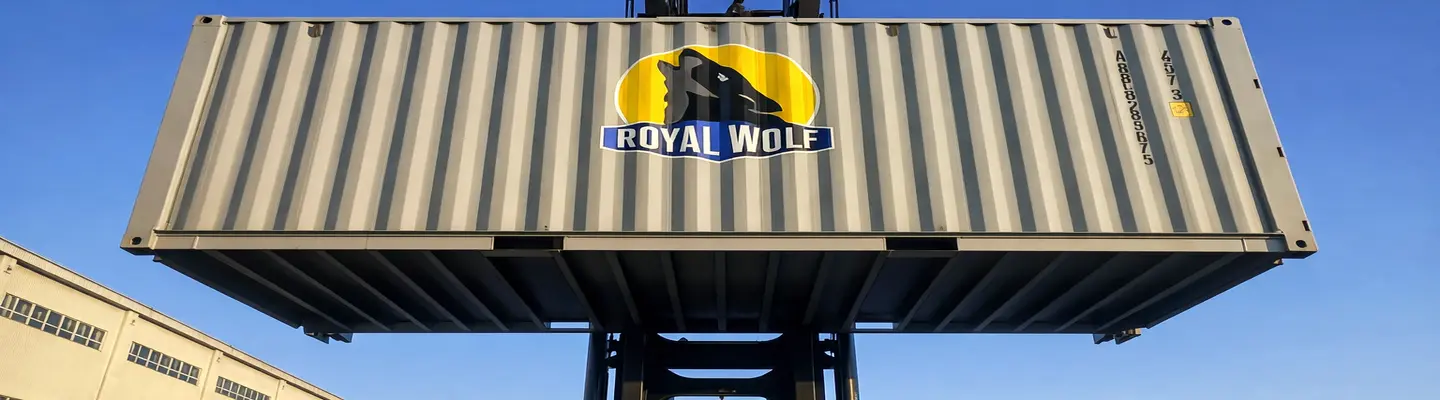 A 20ft Wolf-lock Shipping Container being lifted by a forklift, suspended above the ground in an industrial yard.