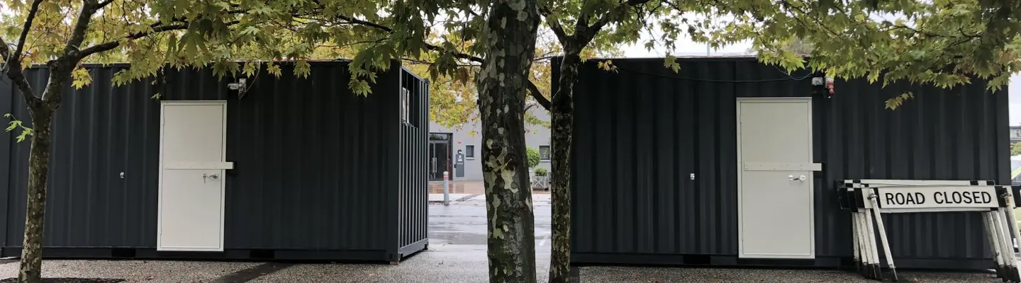 Ticket booth made from a repurposed shipping container, featuring service windows and signage in a compact, functional design.