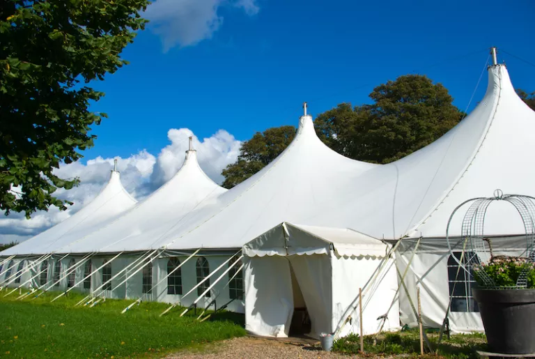 white tents outside on green grass near trees under a blue sky