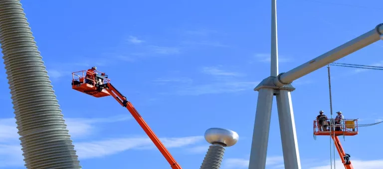 workers on boom lifts at power substation