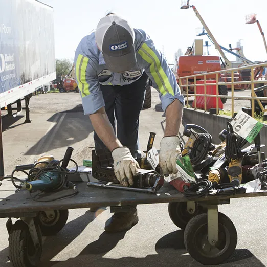 Worker sorting through tools on a dolly
