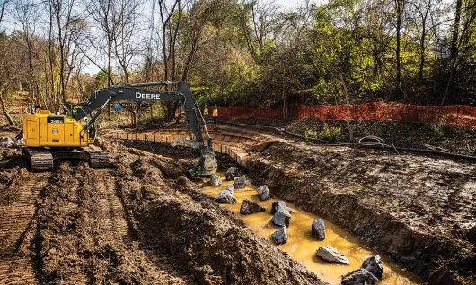 Yellow John Deere excavator digging in the dirt