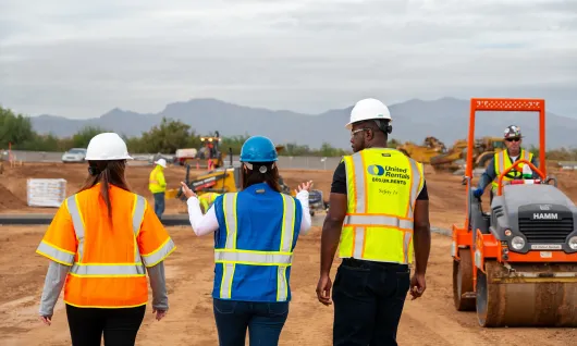 3 people on jobsite walking toward equipment
