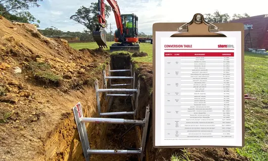 Construction machine near a trench with a conversion table displayed, aiding in accurate measurements and safe installation.