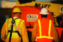 two men in ppe near boom lift