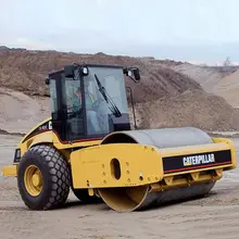 A Caterpillar compaction roller in use on a construction site, compacting soil to prepare a stable foundation for roadwork.
