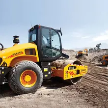 Men operating heavy machinery on a construction site, surrounded by safety barriers and wearing protective gear.