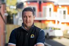 Man standing proudly in front of a shipping container house, representing innovation in modular and sustainable housing design.