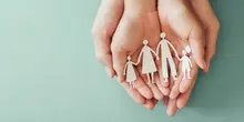 Hands holding a paper cutout of a family symbolizing care and protection.