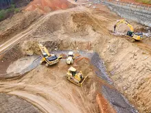"Excavators assisting construction crews on-site, with safety barriers in place to control access and protect workers."